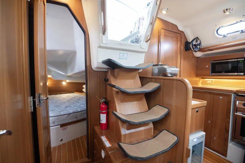 Slide: The Image of Interior of 2024 Catalina 445 yacht featuring kitchen, stairs, and cozy bedroom. - 6
