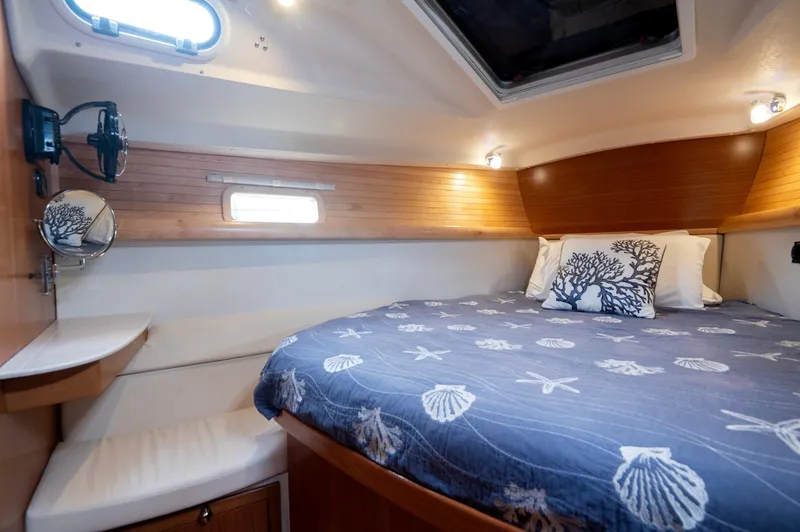 Slide: The Image of 2024 Catalina 445 yacht cabin with cozy bed, nautical-themed bedding, and wooden accents. - 9