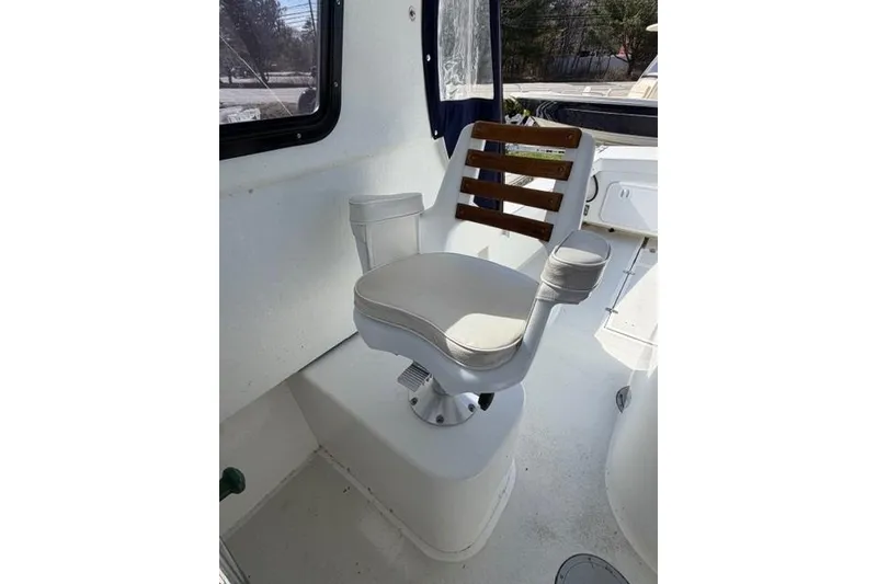 Slide: The Image of Captain's chair on 2020 Eastern 248 Explorer boat, featuring white upholstery and wooden accents. - 9