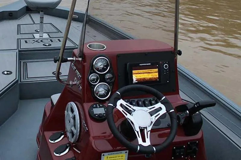Slide: The Image of 2026 Excel 220 Bay Pro Elite boat dashboard with steering wheel and navigation display. - 2