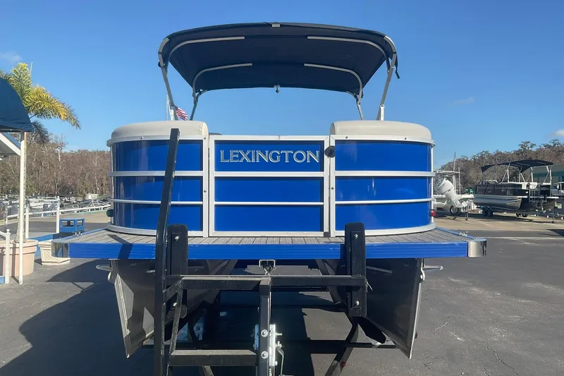 Slide: The Image of 2021 Lexington 318 3 Series pontoon boat with blue exterior, docked under clear skies. - 4