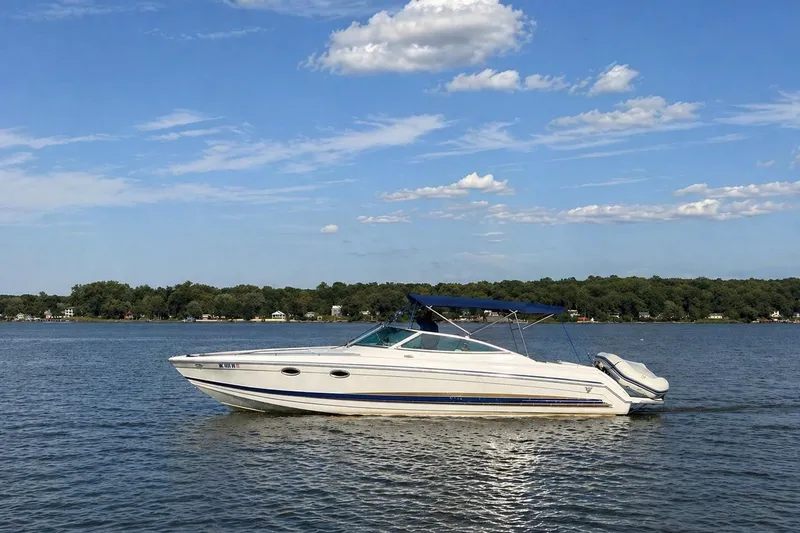 The Image of 2002 Formula 330 Sun Sport boat cruising on a calm lake under a clear blue sky. - 0