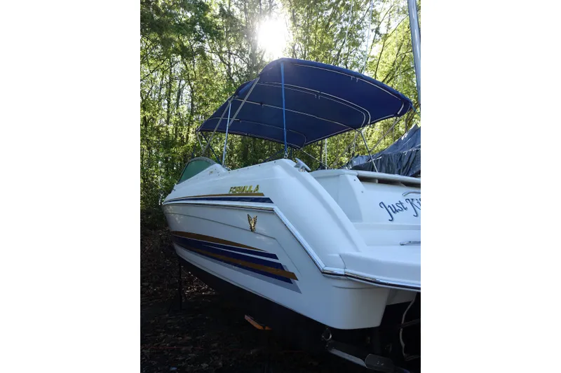 Slide: The Image of 2002 Formula 330 Sun Sport boat with blue canopy in wooded area. - 2