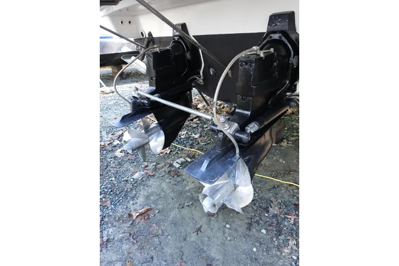 Slide: The Image of 2002 Formula 330 Sun Sport boat propellers and outdrives on gravel surface. - 30
