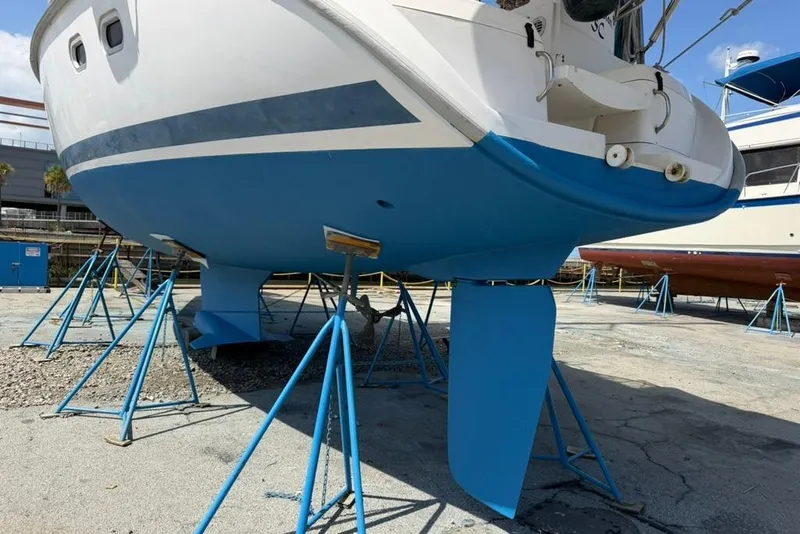 Slide: The Image of Sailboat Hunter 410 (2002) on stands, showcasing blue hull and rudder in a boatyard. - 10