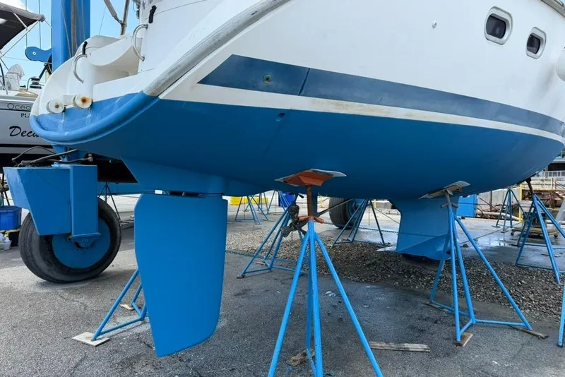 Slide: The Image of Hunter 410 sailboat from 2002 on stands, showcasing blue hull and rudder. - 12