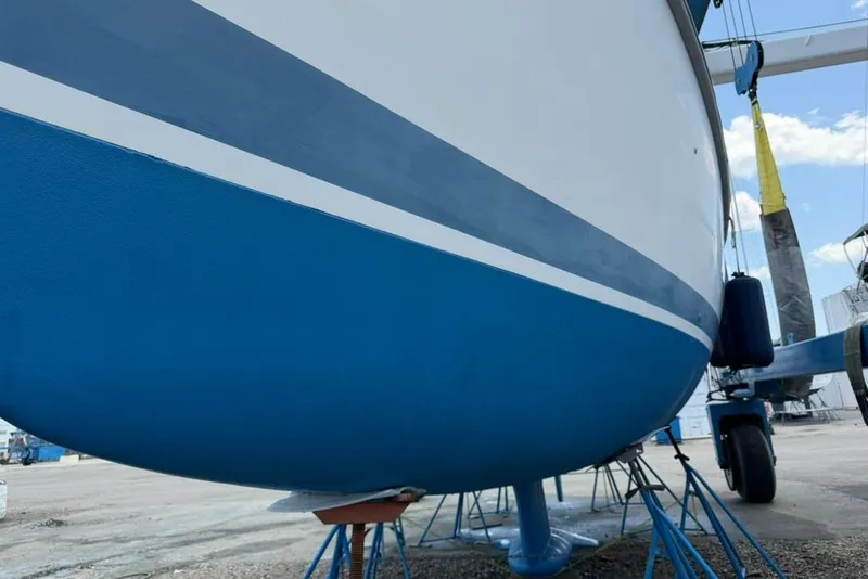 Slide: The Image of Blue and white hull of a 2002 Hunter 410 sailboat on stands in a boatyard. - 13