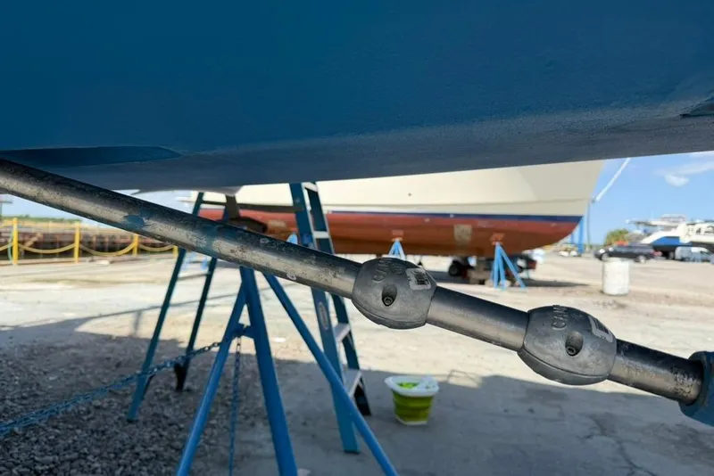 Slide: The Image of 2002 Hunter 410 sailboat on stands, showing hull and propeller shaft in a boatyard. - 15