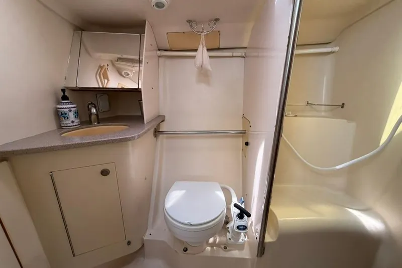 Slide: The Image of Compact bathroom in a 2002 Hunter 410 yacht, featuring a toilet, sink, and shower area. - 49