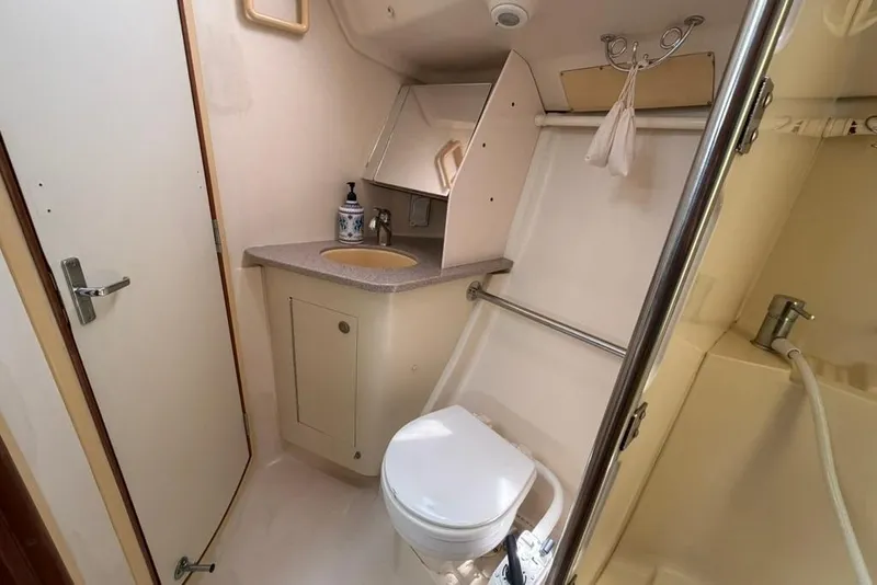 Slide: The Image of Compact bathroom in a 2002 Hunter 410 yacht, featuring a toilet, sink, and shower area. - 51