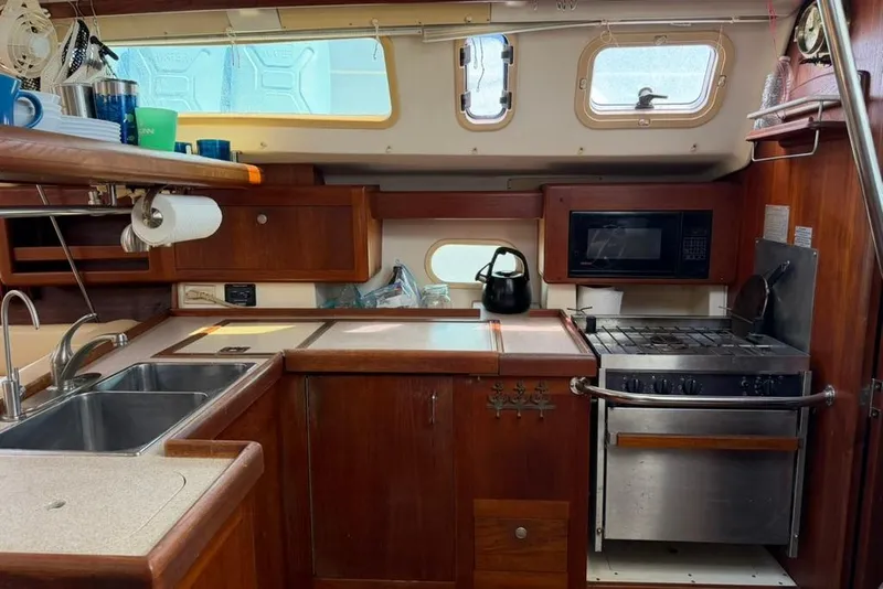 Slide: The Image of 2002 Hunter 410 yacht kitchen with wooden cabinetry, stove, microwave, and sink. - 62
