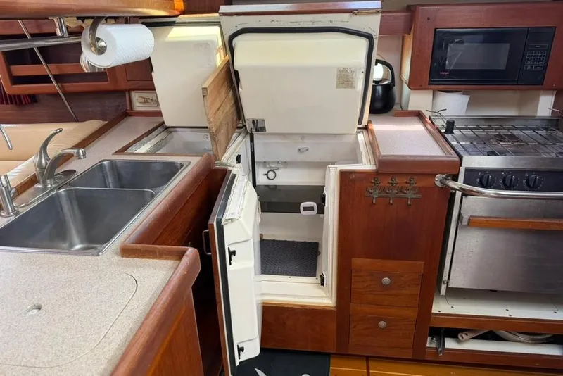 Slide: The Image of 2002 Hunter 410 yacht kitchen with sink, stove, and open refrigerator. - 63