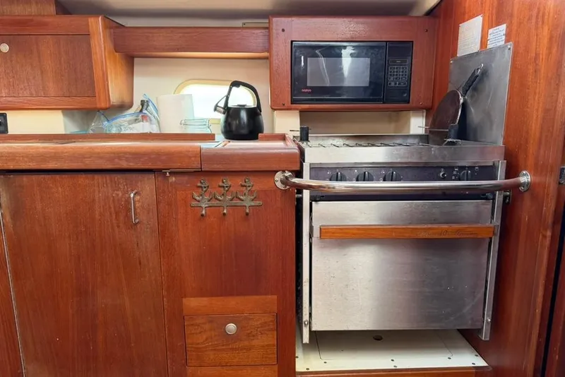 Slide: The Image of 2002 Hunter 410 yacht kitchen with wooden cabinetry, stove, microwave, and kettle. - 66
