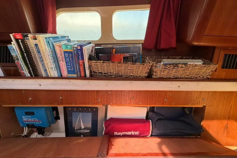 Slide: The Image of Books and navigation equipment on a 2002 Hunter 410 sailboat interior shelf. - 69