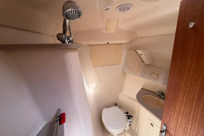 Slide: The Image of Compact bathroom in a 2002 Hunter 410 yacht, featuring a toilet, sink, and showerhead. - 84