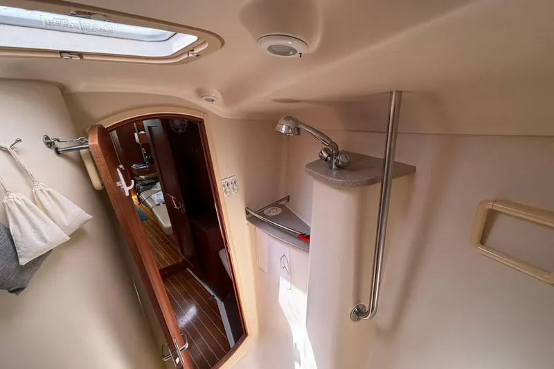 Slide: The Image of Interior of 2002 Hunter 410 sailboat showing compact bathroom with shower and wooden door. - 85