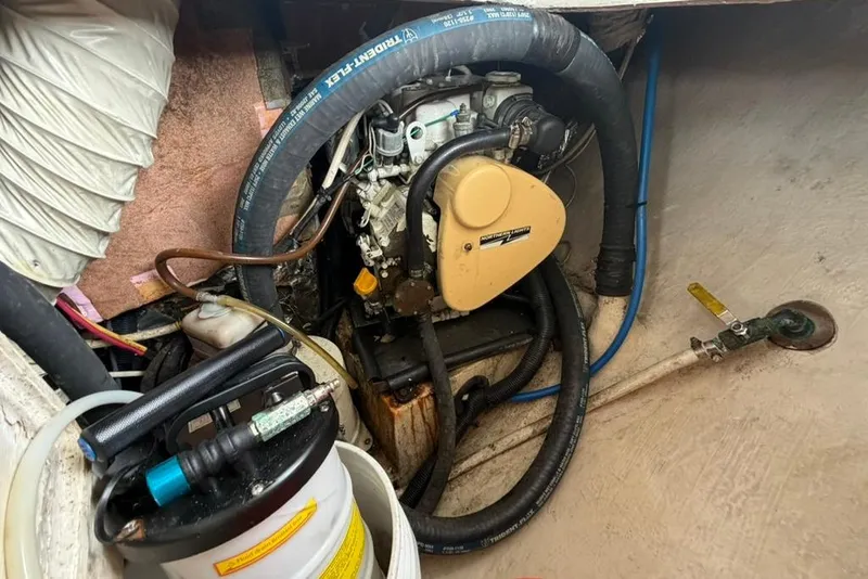 Slide: The Image of Engine compartment of a 2002 Hunter 410 sailboat, featuring hoses and mechanical components. - 89