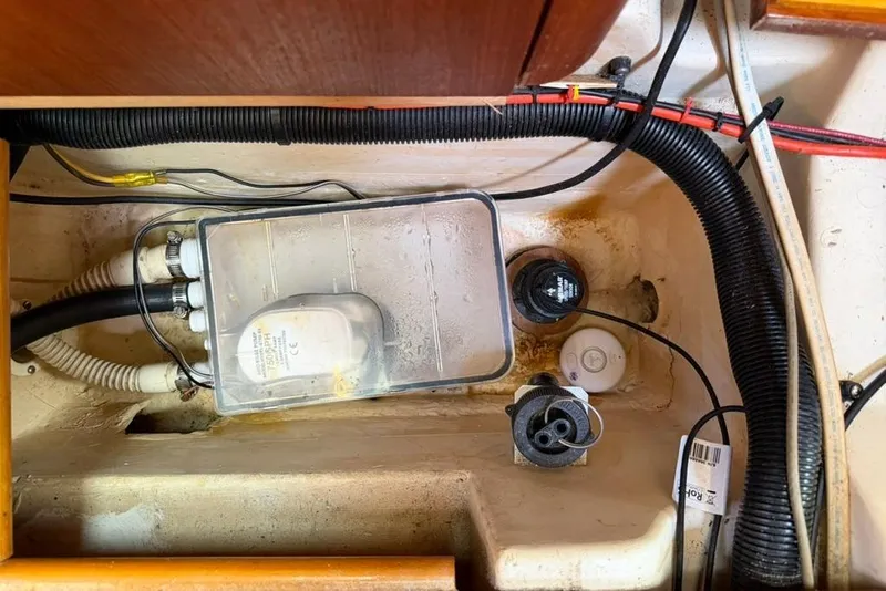 Slide: The Image of Bilge area of a 2002 Hunter 410 sailboat, featuring wiring and pump components. - 97