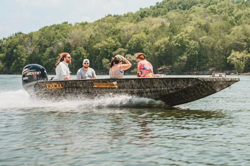 Slide: The Image of 2026 Excel 183 Tomahawk boat cruising on a lake with four passengers, surrounded by lush greenery. - 2