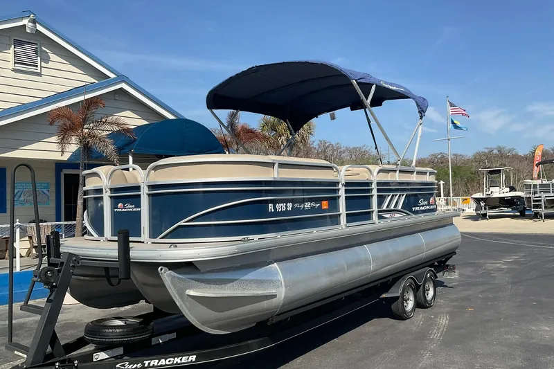 Slide: The Image of 2020 Sun Tracker Party Barge 22 XP3 pontoon boat on trailer, parked near a building. - 4
