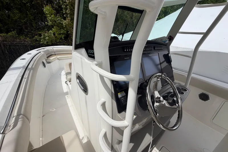 Slide: The Image of 2016 Boston Whaler 330 Outrage boat cockpit with steering wheel and navigation screens. - 13