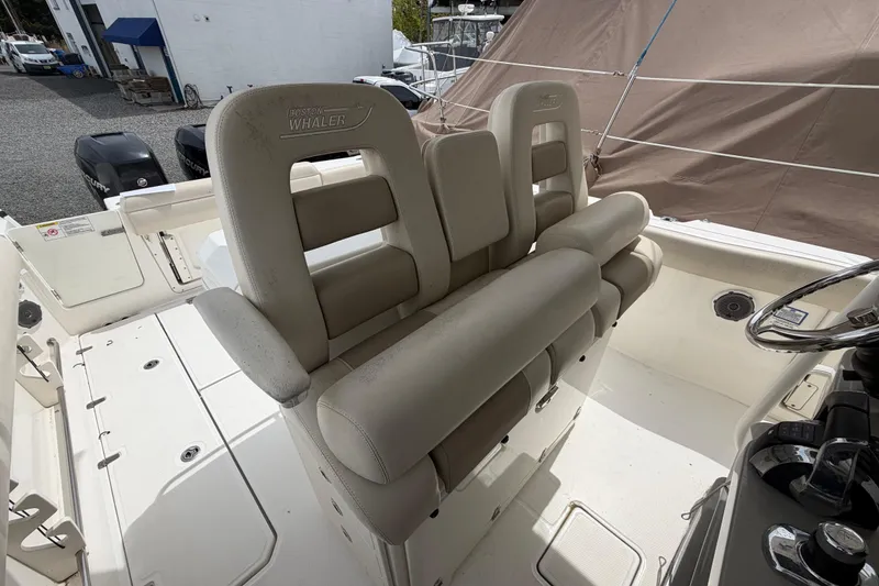 Slide: The Image of Boston Whaler 330 Outrage 2016 boat interior with beige seating and steering wheel. - 28