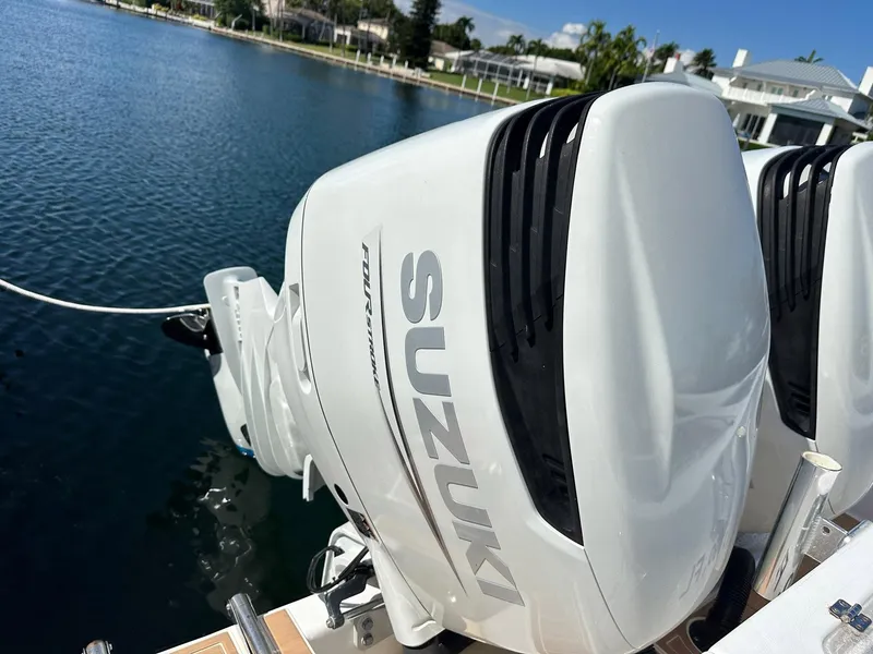 Slide: The Image of Twin Suzuki outboard engines on a 2007 Contender 33 Tournament boat by the water. - 21