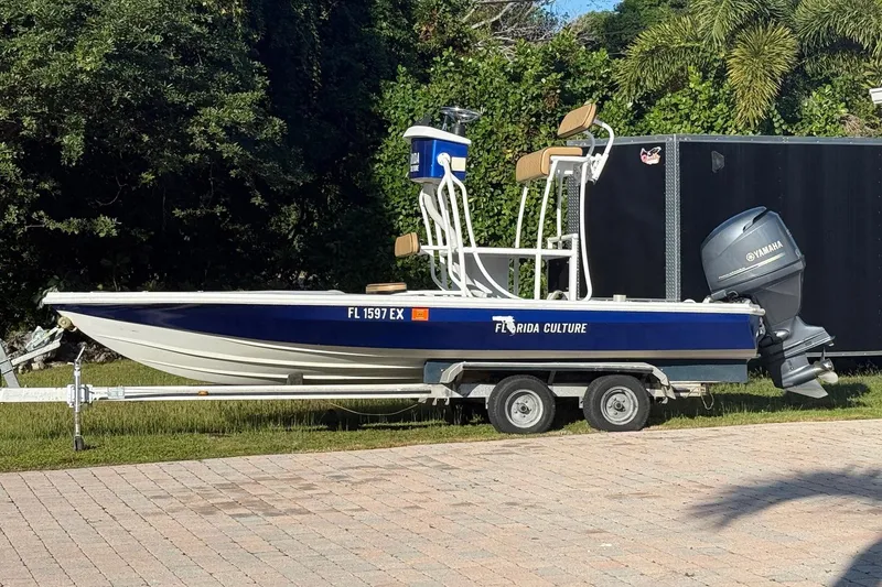 The Image of 1986 Dolphin 18 Skiff boat on trailer with Yamaha outboard motor, parked outdoors. - 1