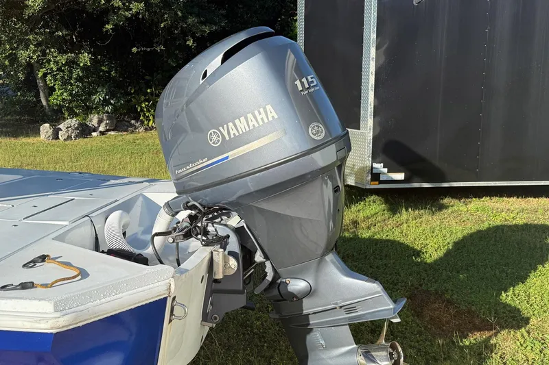 Slide: The Image of 1986 Dolphin 18 Skiff with Yamaha 115 outboard motor, parked on grass. - 8