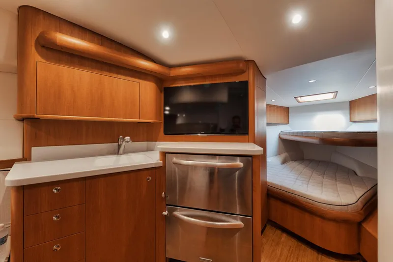 Slide: The Image of Luxurious 2016 F&S Express yacht interior with wood cabinetry, stainless appliances, and cozy sleeping area. - 6