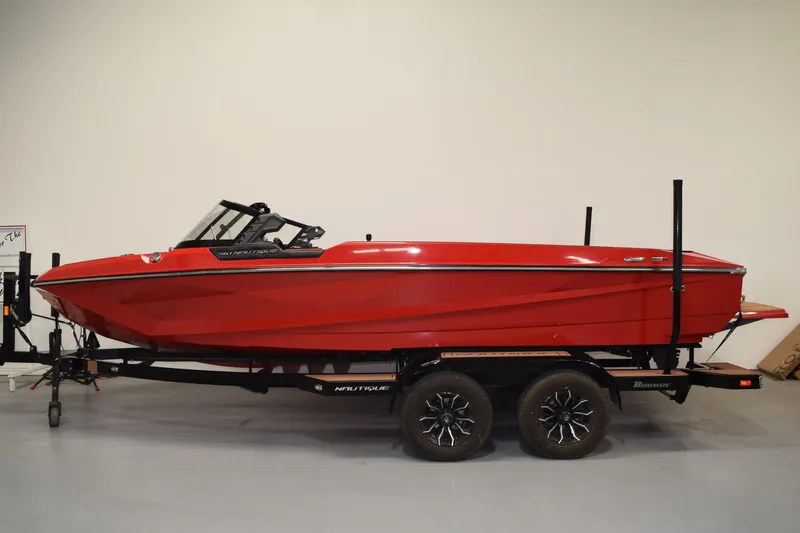 The Image of 2024 red Nautique Ski Nautique boat on trailer in showroom. - 0