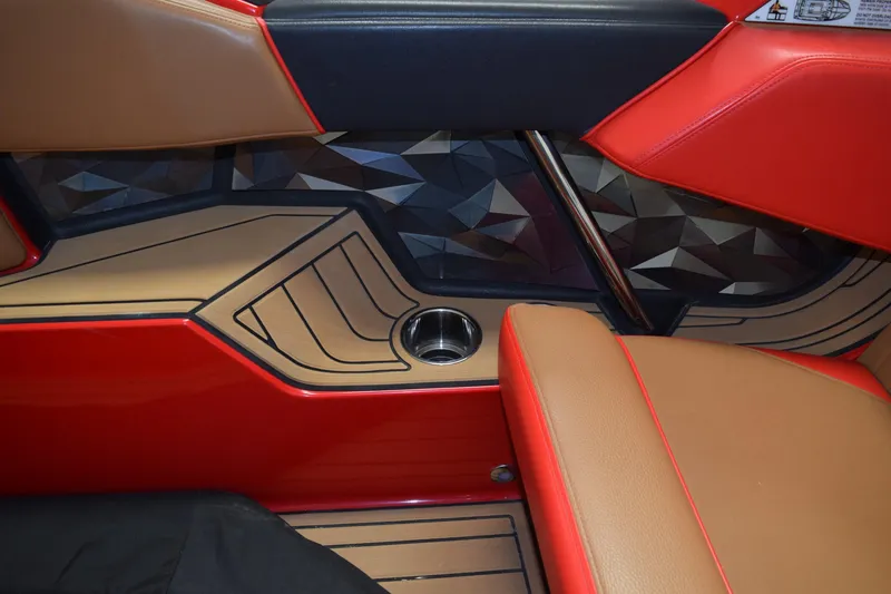 Slide: The Image of 2024 Nautique Ski Nautique interior with red and tan seating, geometric paneling, and cup holder. - 11