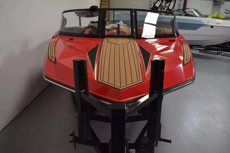 Slide: The Image of 2024 Nautique Ski Nautique boat with red hull and wood accents in showroom. - 13
