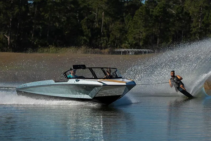 Slide: The Image of Manufacturer Provided Image: 2024 Nautique Ski boat towing a water skier on a calm lake. - 14