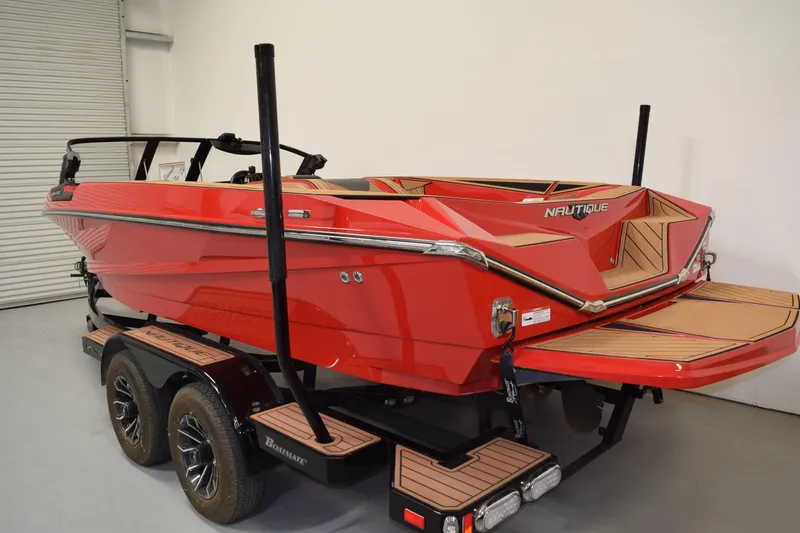 Slide: The Image of 2024 Nautique Ski Nautique boat in vibrant red on a trailer in a garage. - 2