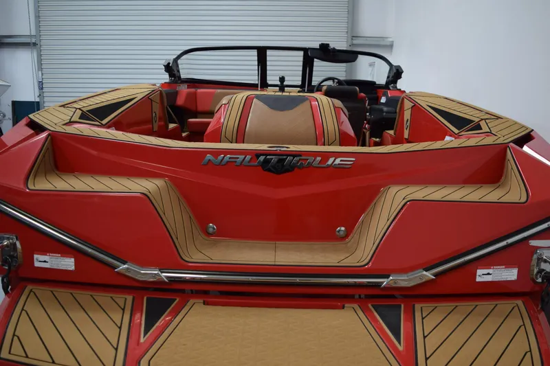 Slide: The Image of 2024 Nautique Ski Nautique boat, red and tan interior, rear view in a garage. - 4