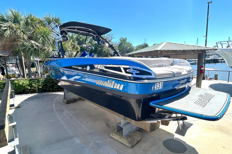 Slide: The Image of 2012 Malibu Wakesetter 247 LSV boat on display, vibrant blue finish, dockside setting. - 4