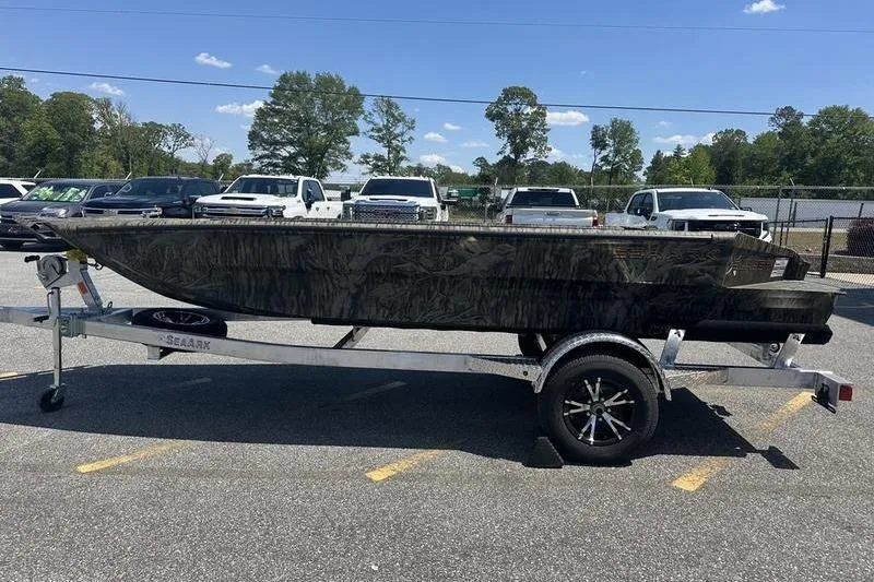 The Image of 2026 SeaArk 1752 Slayer X boat on trailer, parked in lot under clear sky. - 0