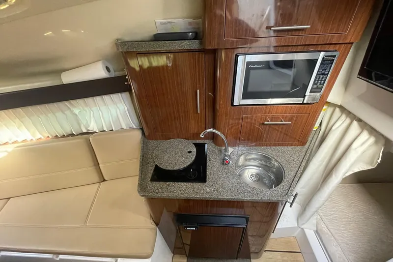 Slide: The Image of 2013 Regal 28 Express boat interior with kitchenette, featuring microwave, sink, and seating area. - 10