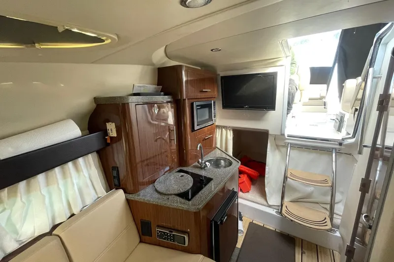 Slide: The Image of Interior of 2013 Regal 28 Express boat with kitchenette, seating, and TV. - 13