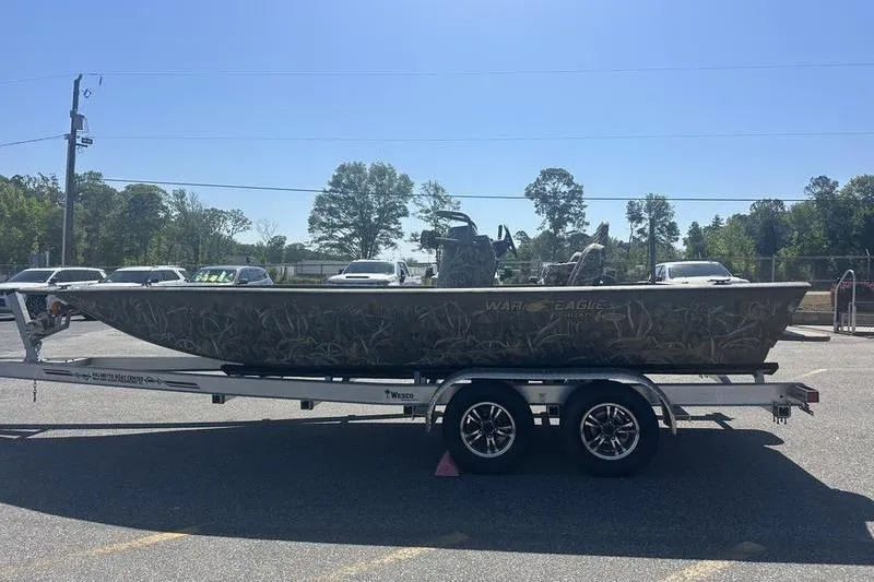 Slide: The Image of 2026 War Eagle 2170 Blackhawk boat on trailer, parked outdoors under clear sky. - 7