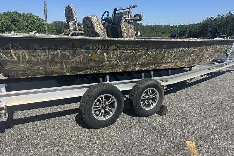 Slide: The Image of 2026 War Eagle 2170 Blackhawk boat on trailer, camo design, parked outdoors. - 8