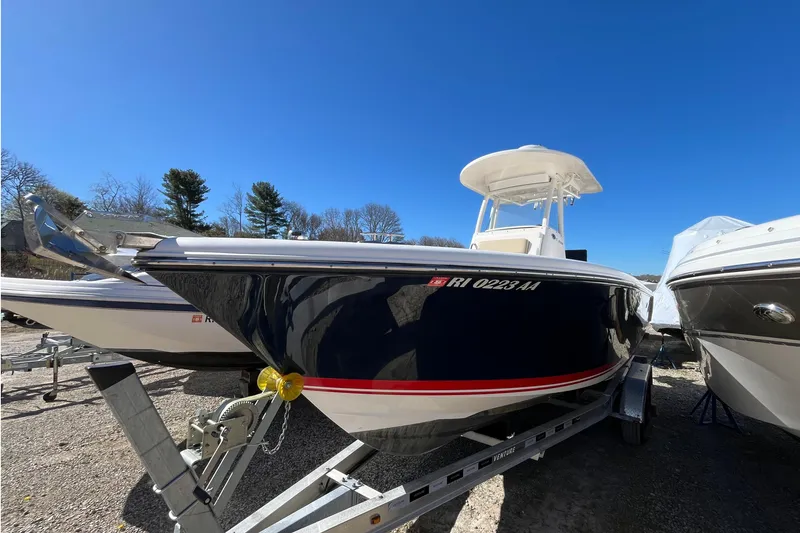 The Image of 2017 Pursuit C 238 Center Console boat on trailer under clear blue sky. - 0