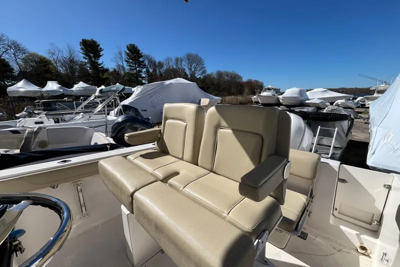 Slide: The Image of 2017 Pursuit C 238 Center Console boat with beige seating, parked outdoors under clear blue sky. - 17
