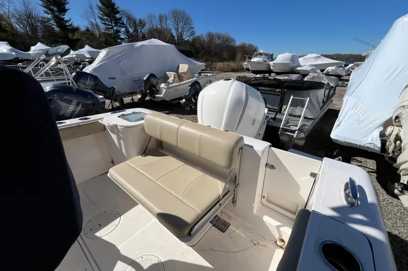 Slide: The Image of 2017 Pursuit C 238 Center Console boat with beige seating, parked among covered boats. - 7
