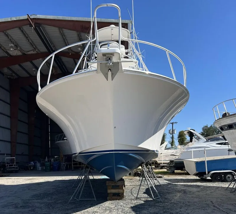 Slide: The Image of 2004 Cabo 40 Express boat in dry dock, front view, under clear blue sky. - 17