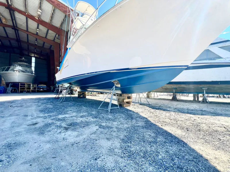 Slide: The Image of 2004 Cabo 40 Express boat in dry dock, supported by stands, under a metal roof. - 18