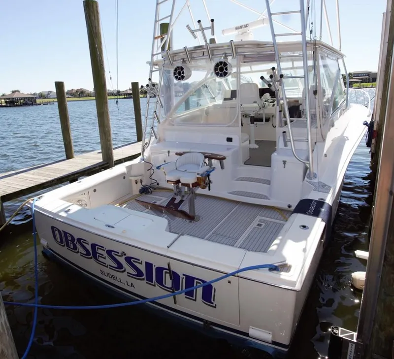Slide: The Image of 2004 Cabo 40 Express boat docked, featuring fishing chair and "Obsession" name on stern. - 3