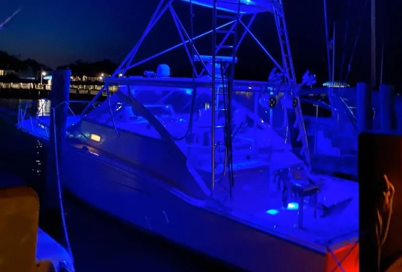 Slide: The Image of 2004 Cabo 40 Express yacht illuminated with blue lights at night. - 9
