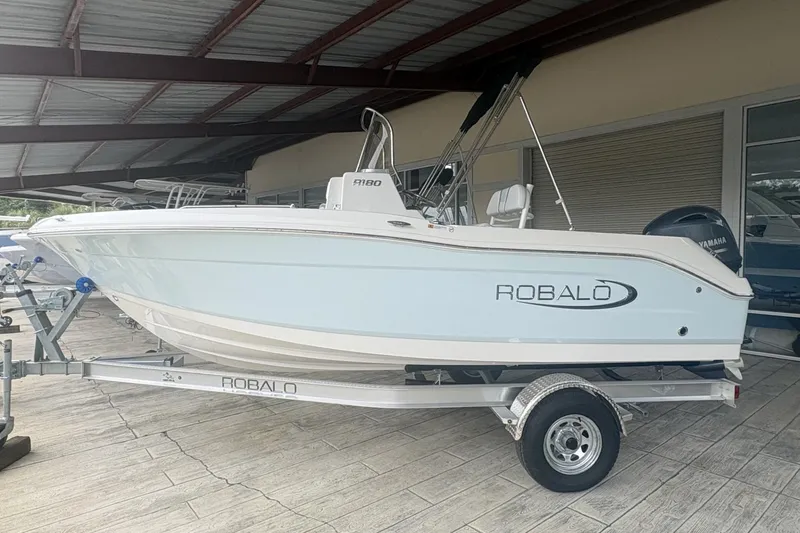 The Image of 2026 Robalo R180 Center Console boat on trailer in showroom. - 0